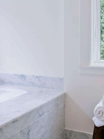 Helle Badewanne neben einem Fenster mit Blick ins Grüne