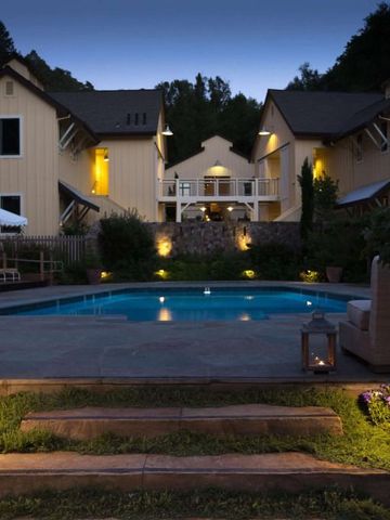 Beleuchtetes Hotelgebäude bei Nacht mit Pool und Garten im Vordergrund