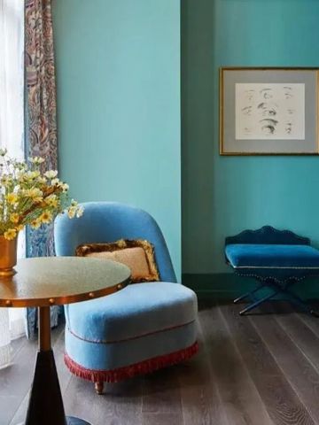 Eleganter Sitzbereich mit hellblauer Wand und dekorativem Stuhl.