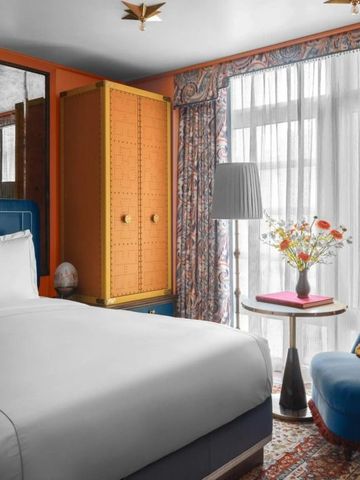 Geschmackvoll eingerichtetes Hotelzimmer mit Blumenstrauß auf dem Beistelltisch.