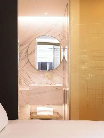 Helles Badezimmer mit Marmordekor und rundem Spiegel