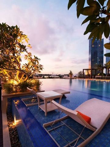 Infinity Pool bei Sonnenuntergang mit modernen Liegestühlen und Stadtblick