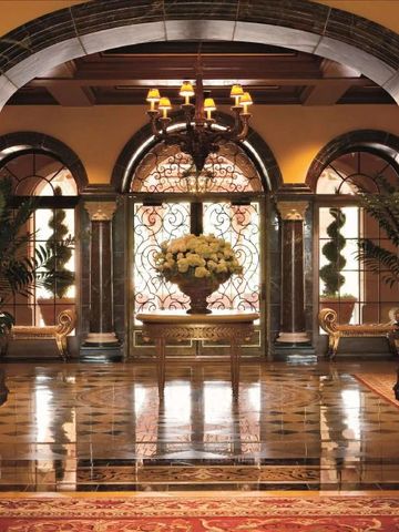 Elegante Hotellobby mit Marmorsäulen und Blumenarrangement.