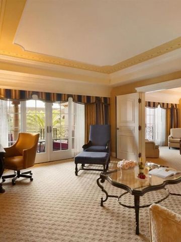 Geräumiges Wohnzimmer einer luxuriösen Hotelsuite mit eleganten Möbeln und Balkonzugang