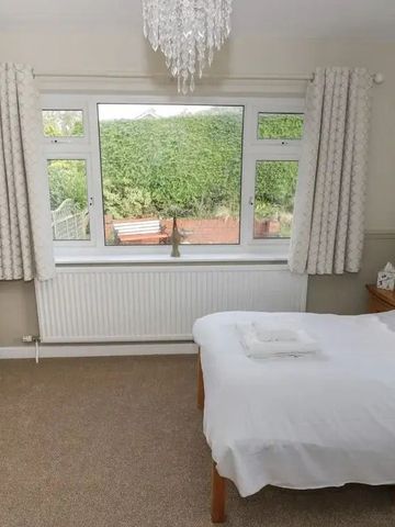 Helles Schlafzimmer mit großen Fenstern und Gartenblick