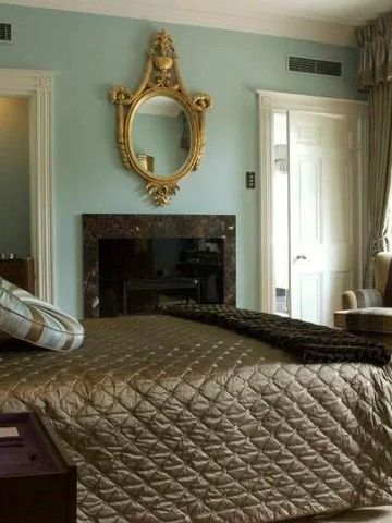 Luxuriöses Schlafzimmer mit antikem Spiegel und eleganten Stoffen.