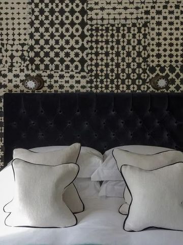 Doppelbett mit gemustertem Hintergrund in Hotelzimmer