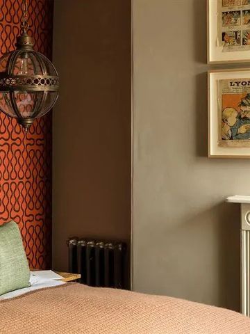 Elegantes Hotelzimmer mit Kamin, farbenfroher Tapete und stilvoller Kunst.