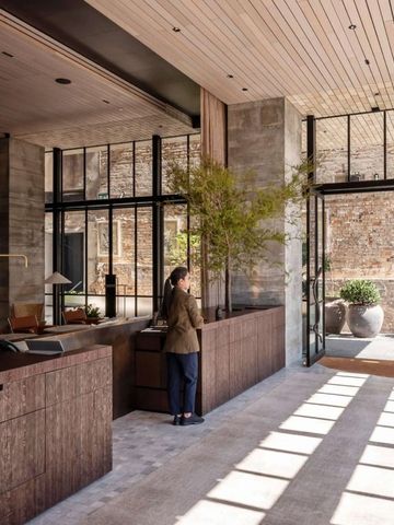 Stilvolle Hotel-Lobby mit Holz- und Steinelementen großen Fenstern und Pflanzen
