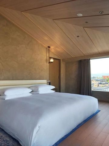 Geräumiges Zimmer mit großem Bett und Panoramablick auf die Stadt