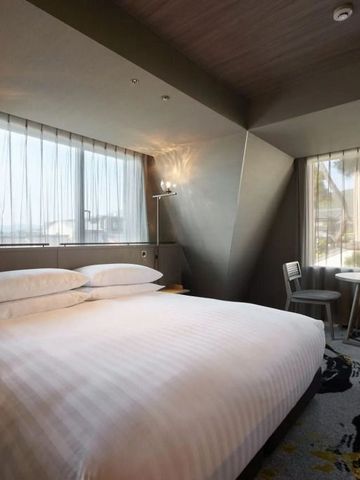 Komfortables Hotelzimmer mit großem Bett und zwei Fenstern