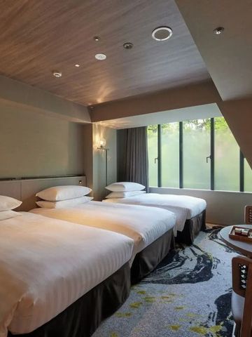 Hotelzimmer mit drei Einzelbetten und großen Fenstern