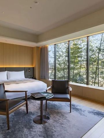 Geräumiges Hotelzimmer mit großen Fenstern und Blick auf einen Bambusgarten