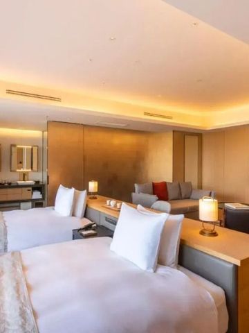 Elegantes modernes Hotelzimmer mit zwei Betten, gemütlichem Sofa und stilvoller Beleuchtung.