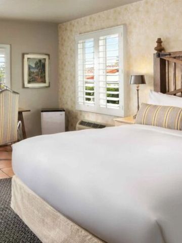 Helles Zimmer mit gemütlichem Bett und Schreibtisch neben Fenstern mit Fensterläden