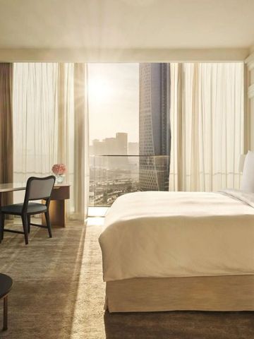 Helles Zimmer mit großem Bett, Schreibtisch und Blick auf die Stadt bei Sonnenaufgang