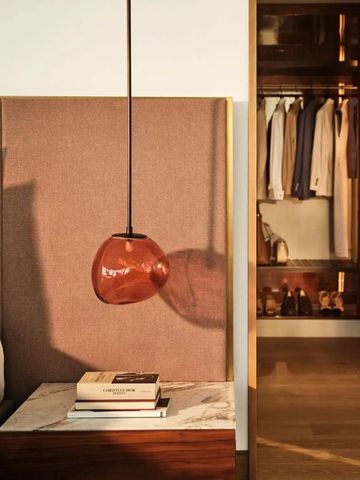 Moderne Nachttischlampe neben einem Bett mit Blick in einen begehbaren Kleiderschrank.