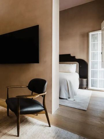 Modernes Hotelzimmer mit großem Flachbildfernseher und komfortablem Sessel.