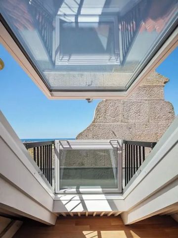Dachfenster mit Blick auf strahlend blauen Himmel und Steinmauern