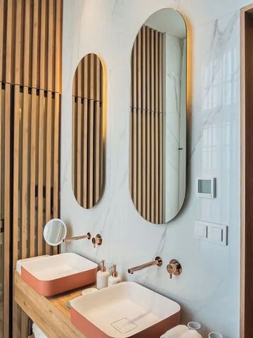 Hotelbadezimmer mit Holzvertäfelung und ovalen Spiegeln