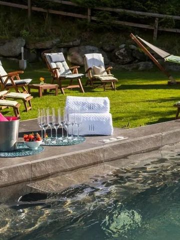 Entspannungsbereich am Außenpool mit Liegestühlen und Handtüchern in einer grünen Gartenlandschaft.