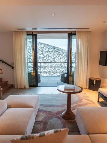 Hell eingerichtetes Wohnzimmer mit Zugang zu einem Balkon und Aussicht auf verschneite Berge