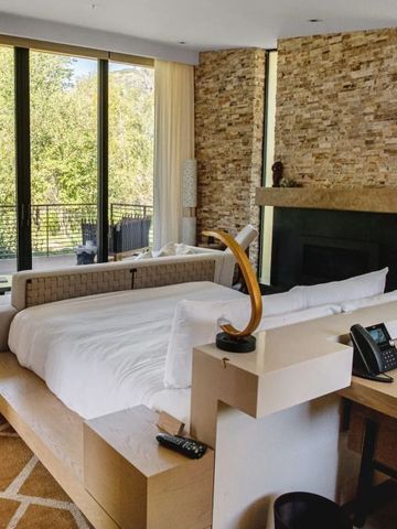 Elegantes Schlafzimmer mit Kamin und großem Fenster mit Blick ins Grüne