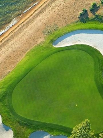 Grünes Golfplatzgelände am Rande des Sees in malerischer Umgebung