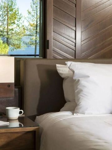 Gemütlicher Hotelzimmerbereich mit Blick auf Bäume und See durch große Fenster