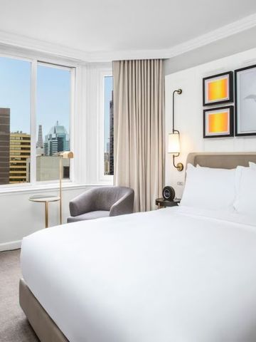 Helles Schlafzimmer mit großem Fenster und Stadtblick