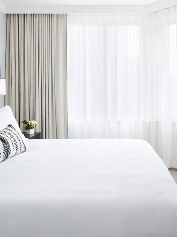 Helles Zimmer mit großem Bett, weißen Vorhängen und modernen Akzenten