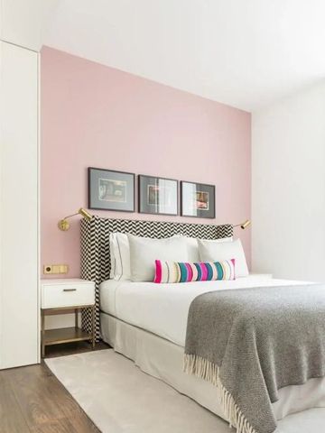 Helles Schlafzimmer mit geometrischem Kopfteil und Kunstwerken an der Wand