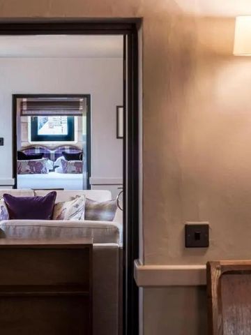 Blick durch die Tür in ein einladendes Wohnzimmer mit weichen Sofas im Lygon Arms.