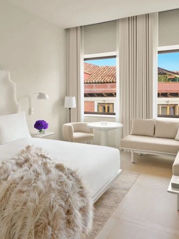 Helles Zimmer mit gemütlicher Sitzecke und Fenstern mit Stadtblick.