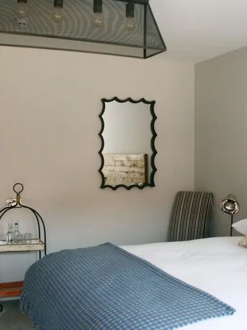 Elegantes Schlafzimmer mit großem Spiegel, Bett und moderner Leuchte