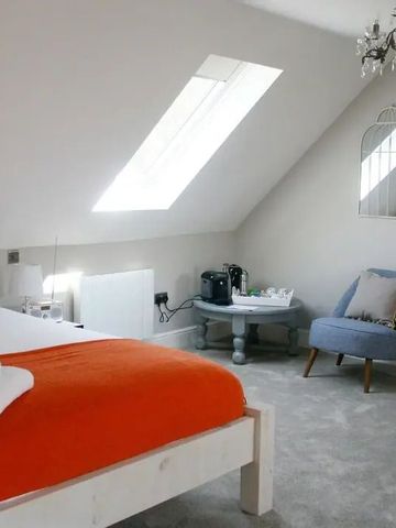 Luxuriöses Schlafzimmer mit Dachfenstern und gemütlicher Sitzecke