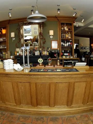 Barbereich mit Holztheke und diversen Flaschen im Hintergrund