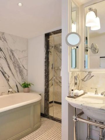 Geräumiges Badezimmer mit freistehender Badewanne und Marmordetails