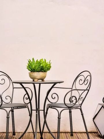 Metalltisch mit Stühlen und Pflanze auf Terrasse