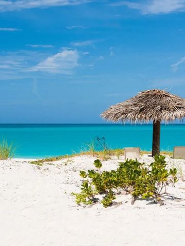 Weißer Sandstrand mit Strohhütte und türkisfarbenem Meer