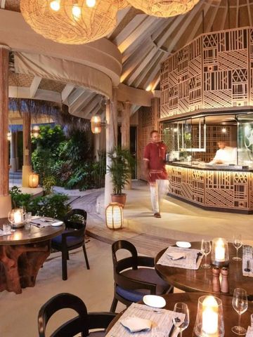 Elegantes Restaurant mit runden Tischen und moderner offener Küche