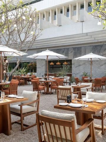 Gemütlicher Außenbereich eines Restaurants mit Tischen unter weißen Sonnenschirmen