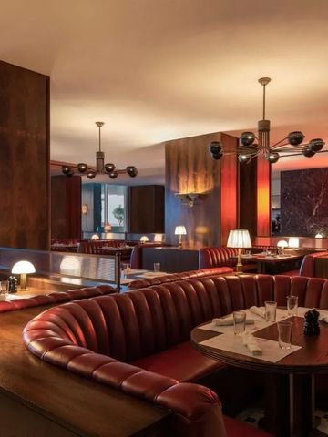 Stilvolles Interieur eines Restaurants mit roten, geschwungenen Sofas und edler Beleuchtung