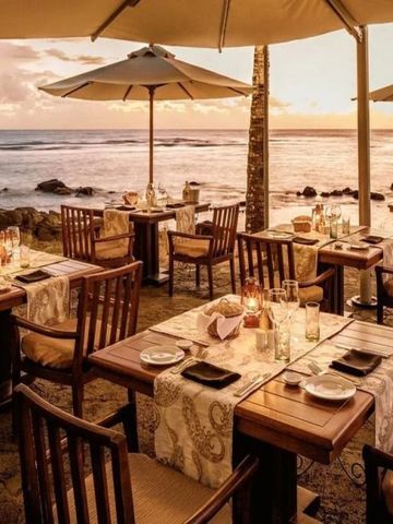 Romantische Strandterrasse mit gedeckten Tischen und Meerblick im Sonnenuntergang