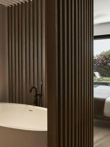 Freistehende Badewanne neben Schlafzimmer mit Gartenblick