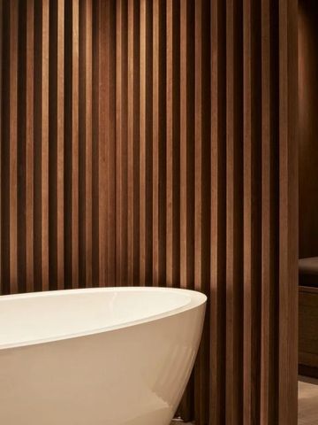 Moderner Badezimmerbereich mit freistehender Badewanne und Holzverkleidung