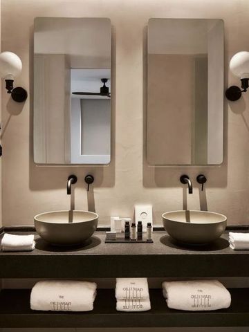 Modernes Badezimmer mit zwei Waschbecken, eleganten Spiegeln und dezenter Beleuchtung
