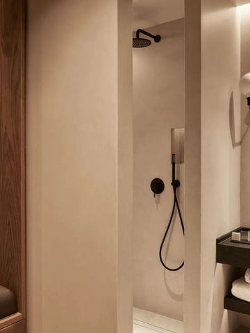Moderne, minimalistische Dusche in einer Hotelsuite mit natürlichen Holzakzenten