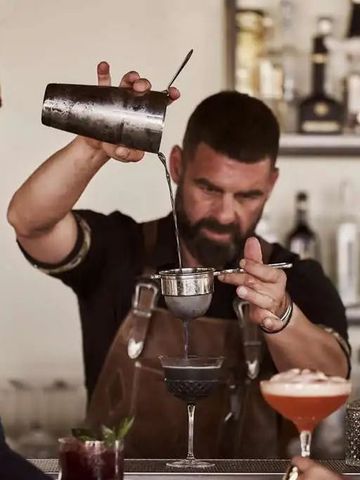 Barmann mixt Cocktails an einer stilvollen Hotelbar mit hochwertigen Spirituosen