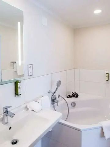 Helles Badezimmer mit Eckbadewanne und Waschbecken